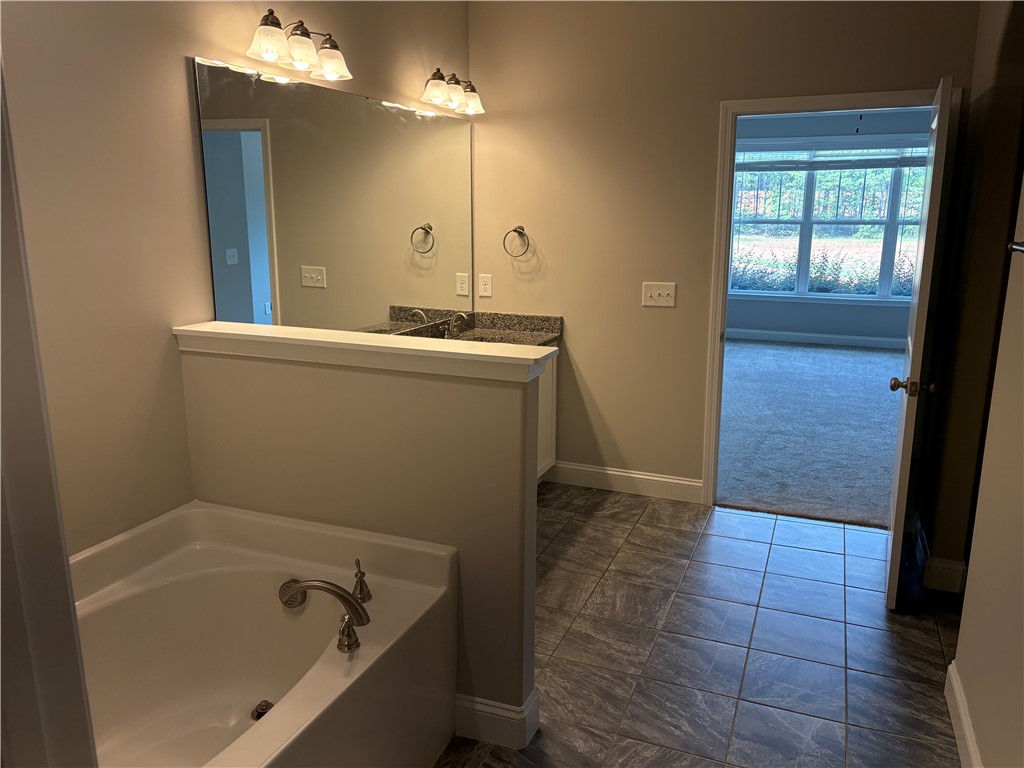 240 Meridian Way Seneca, SC 29672 - Photo 9 of 19 A well-lit bathroom with tile flooring, a built-in tub, and a spacious vanity with dual sinks.