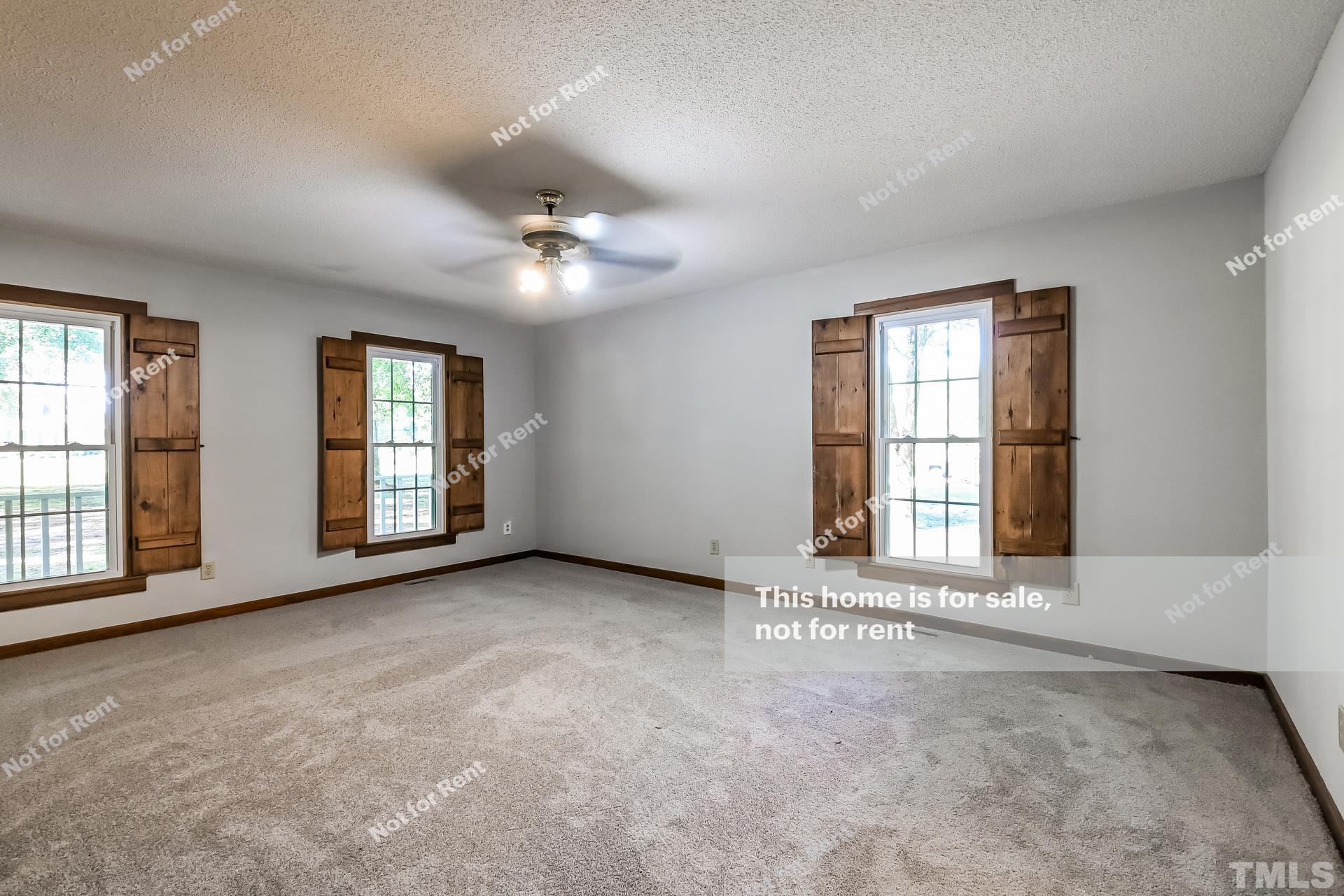 6587 Dwight Rowland Road Willow Spring, NC 27592 - Photo 13 of 25 an empty room with windows and ceiling fan