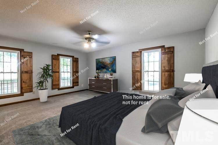 6587 Dwight Rowland Road Willow Spring, NC 27592 - Photo 3 of 25 a spacious bedroom with a bed a couch and dresser with wooden floor