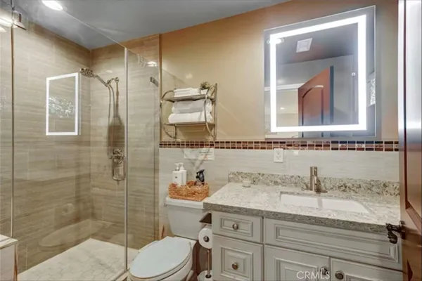a bathroom with a granite countertop sink a mirror and a shower