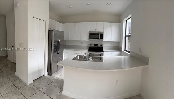 a kitchen with stainless steel appliances a refrigerator a sink a stove a microwave and cabinets