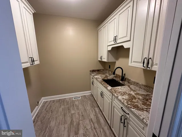 a kitchen with granite countertop a sink stove and cabinets
