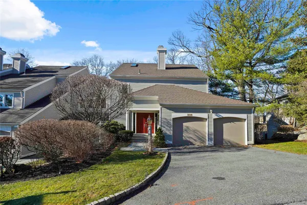 a view of a white house next to a yard with a large tree
