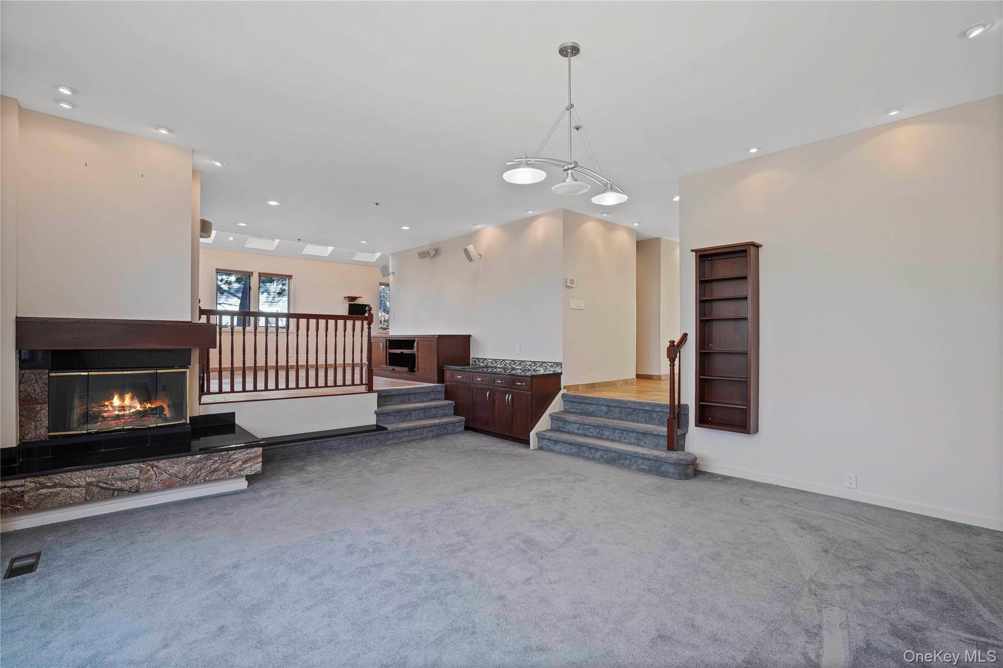 208 Boulder Ridge Road Scarsdale, NY 10583 - Photo 11 of 43 Unfurnished living room with recessed lighting, stairs, a glass covered fireplace, and light colored carpet