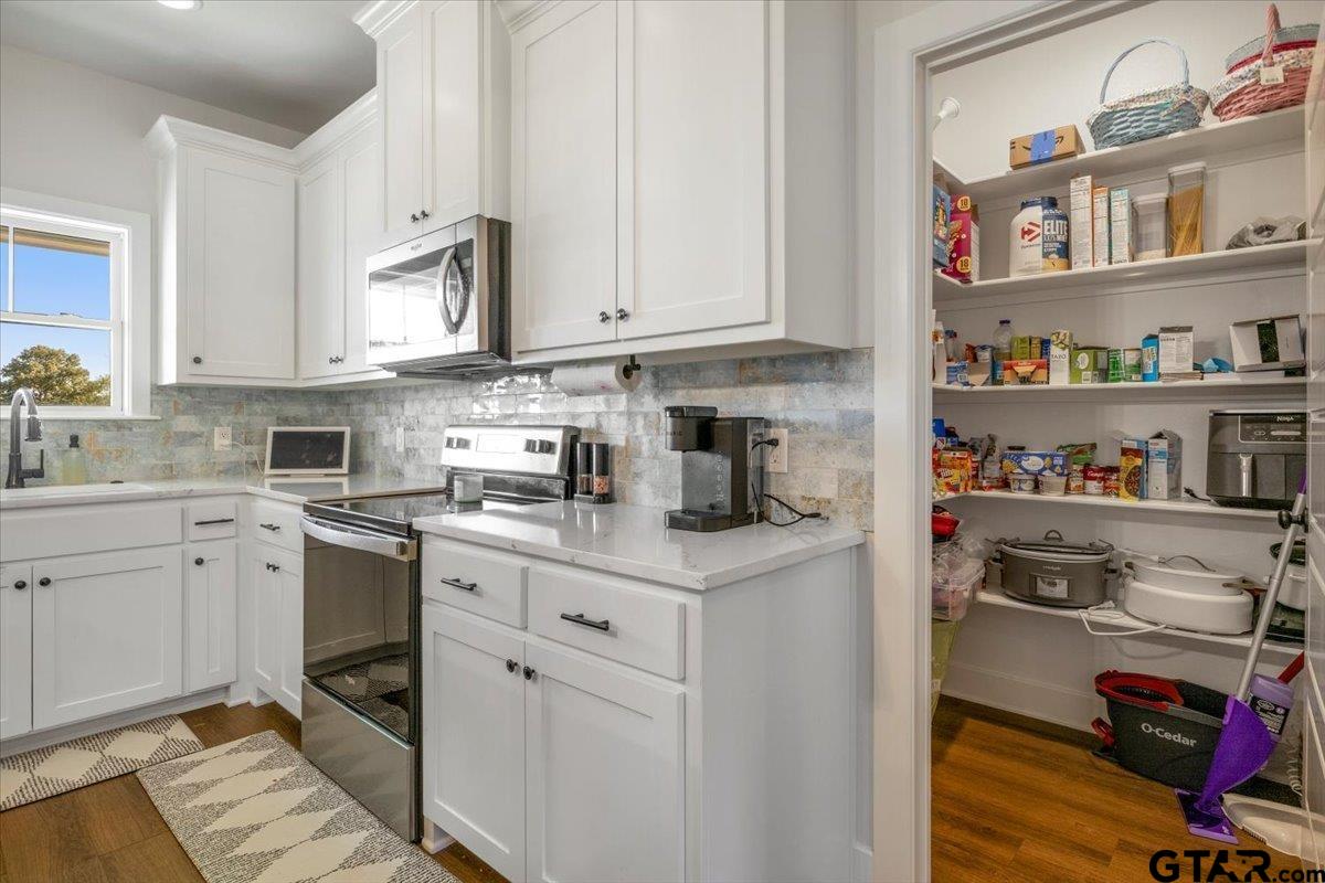 681 Peavine Road Kilgore, TX 75662 - Photo 12 of 27 a kitchen with stainless steel appliances granite countertop a sink dishwasher stove and white cabinets