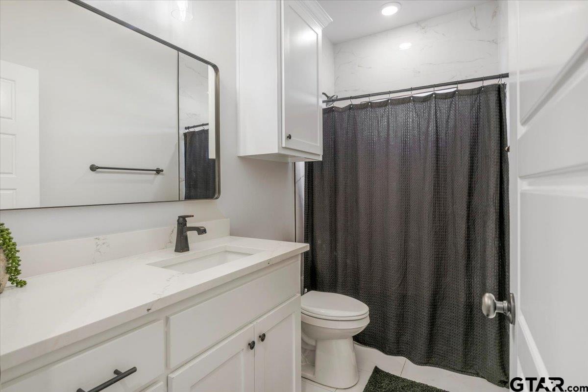 681 Peavine Road Kilgore, TX 75662 - Photo 23 of 27 a bathroom with a sink a toilet a mirror and shower curtain
