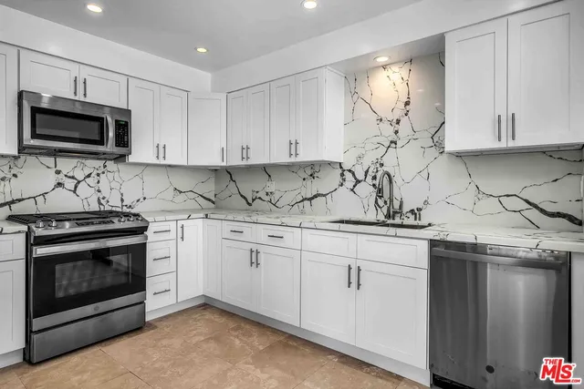 a kitchen with granite countertop white cabinets stainless steel appliances and sink