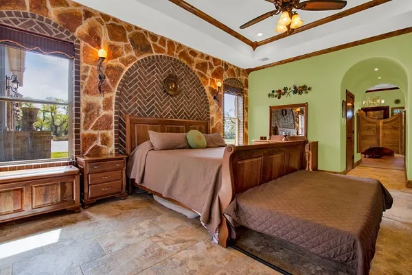 a bedroom with a bed a mirror on dresser and a chandelier