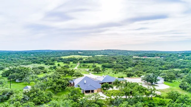 an aerial view of residential house with outdoor space and trees all around