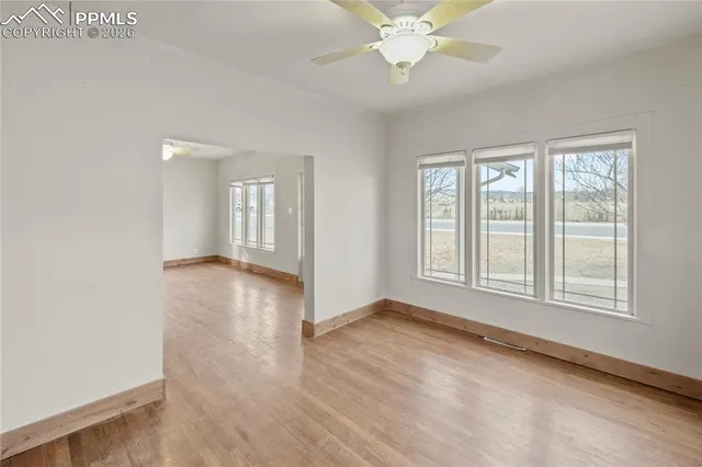 an empty room with wooden floor and windows