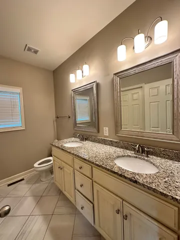 a bathroom with a granite countertop sink a toilet and a mirror