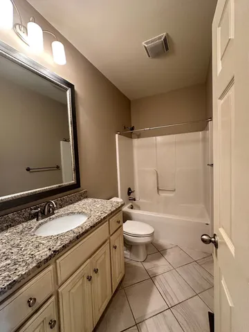 a bathroom with a granite countertop sink toilet mirror and bathtub