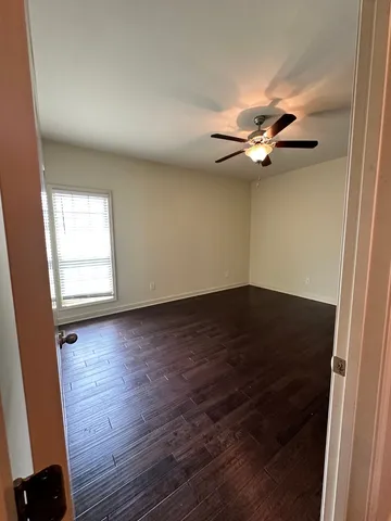 an empty room with wooden floor fan and windows