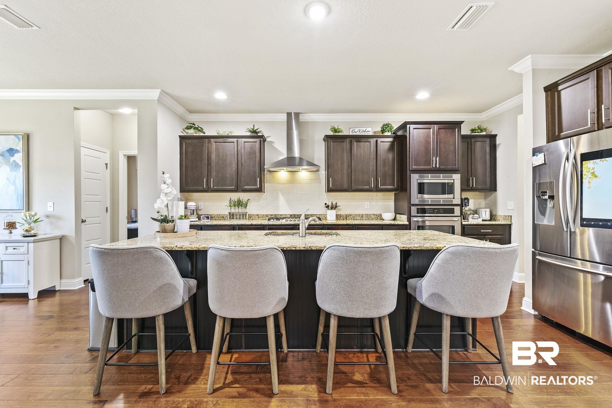 31500 Spoonbill Road Daphne, AL 36527 - Photo 16 of 85 Kitchen featuring a kitchen island with sink, stainless steel appliances, wall chimney exhaust hood, and dark wood-type flooring