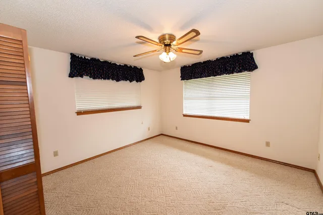 an empty room with windows and fan