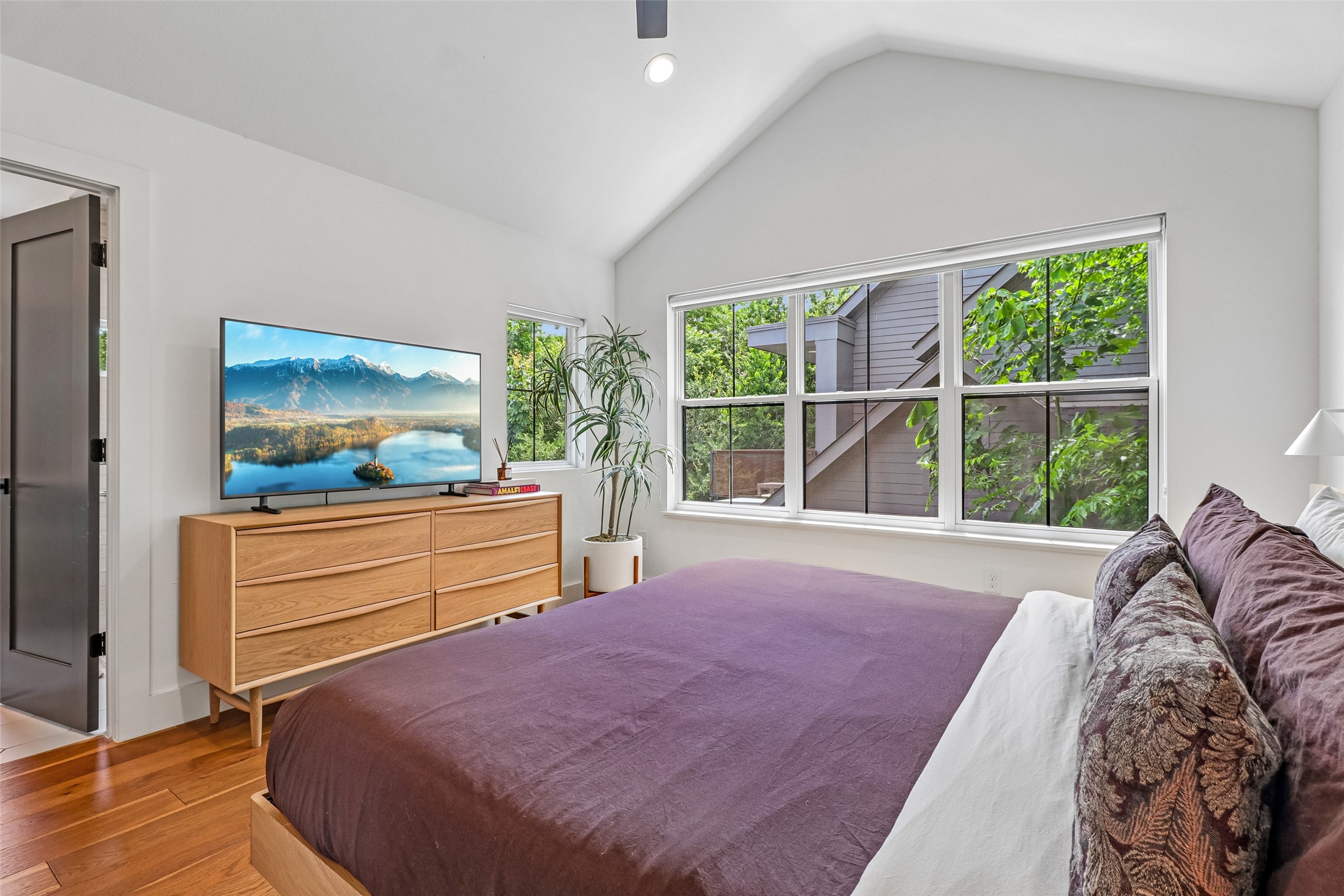 1706 Perez Street, Unit 1 Austin, TX 78721 - Photo 25 of 36 A restful primary bedroom featuring high vaulted ceilings and broad windows capturing serene green views.