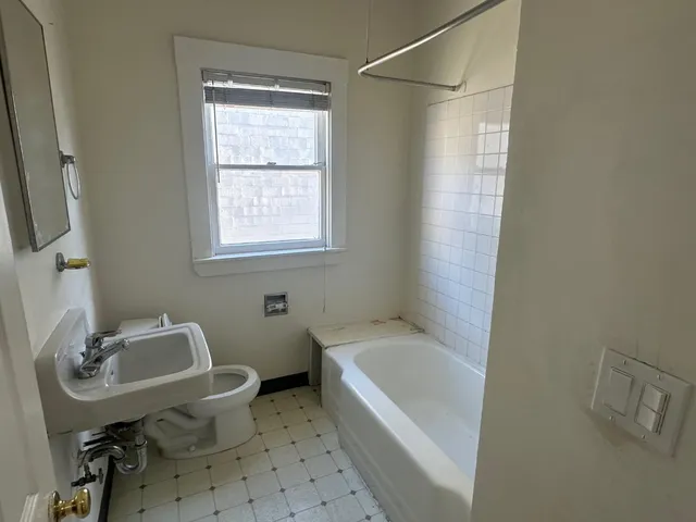 a bathroom with a sink a bathtub and a window