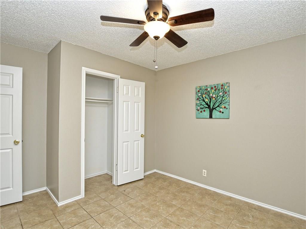 5401 Spring Meadow Road, Unit B Austin, TX 78744 - Photo 19 of 21 A comfortable bedroom features a ceiling fan, tile flooring, and closet for optimal living.