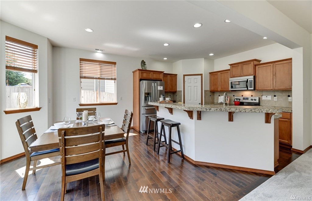 23007 42nd Drive Southeast Bothell, WA 98021 - Photo 4 of 29 a kitchen with stainless steel appliances kitchen island granite countertop a refrigerator a stove a sink a dining table and chairs with wooden floor