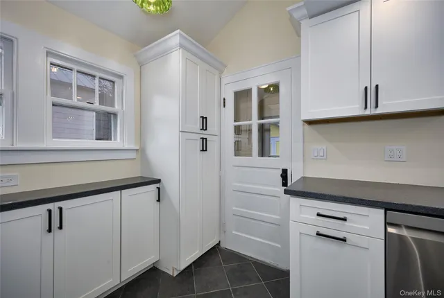 a kitchen with white cabinets and a window