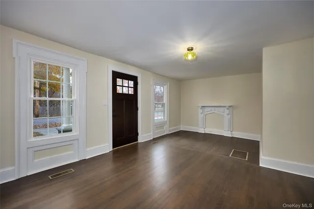 a view of an empty room with window and wooden floor