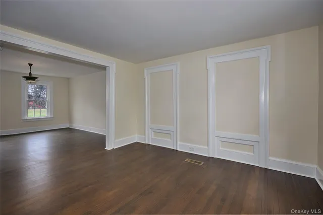an empty room with wooden floor closet and windows