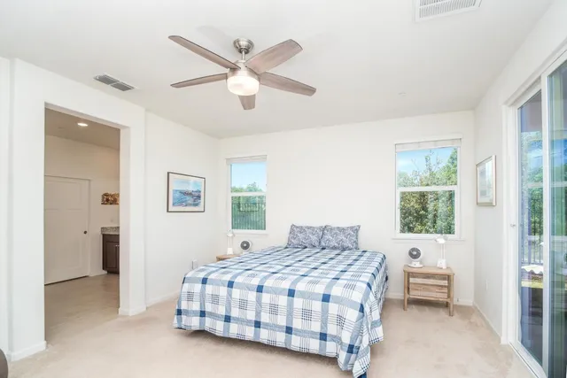 a bedroom with a large bed and a chandelier fan