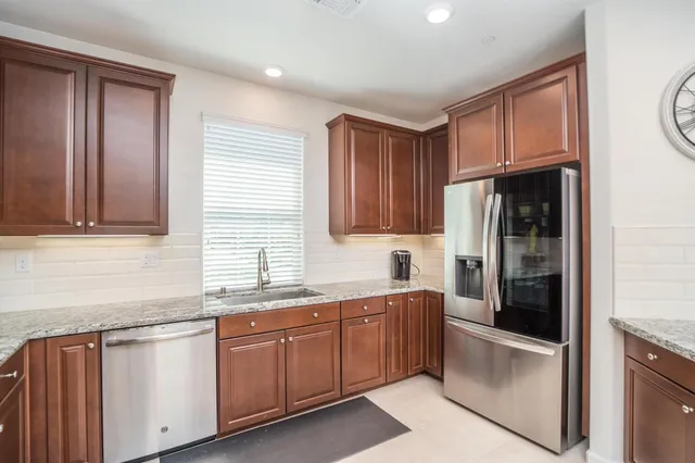 a kitchen with stainless steel appliances kitchen island granite countertop a refrigerator and a sink