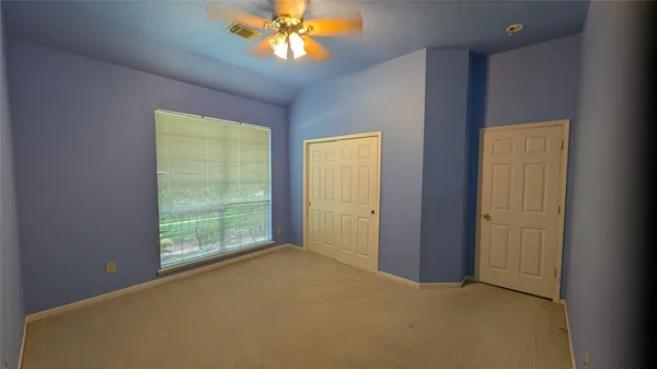 an empty room with windows and chandelier fan
