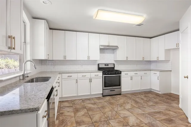 a kitchen with granite countertop a sink stove and cabinets