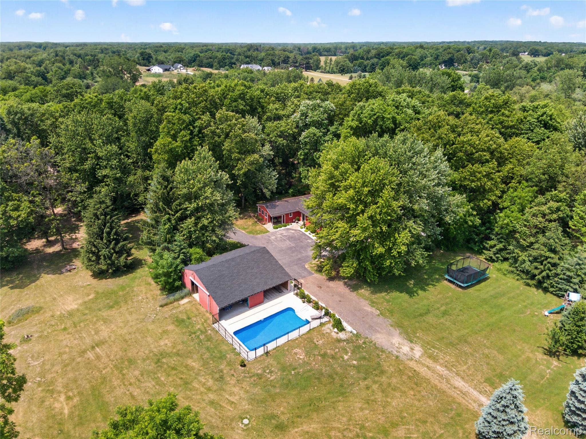 13635 Unadilla Road Gregory, MI 48137 - Photo 57 of 68 Expansive outdoor space featuring a covered swimming pool, a separate red barn structure, and a gravel driveway