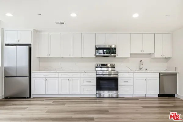 a kitchen with white cabinets and stainless steel appliances