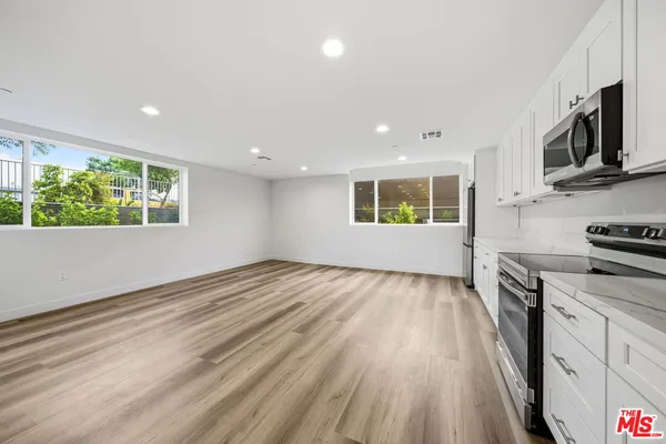a view of a kitchen with wooden floor and electronic appliances