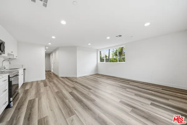 a view of empty room with wooden floor and fan