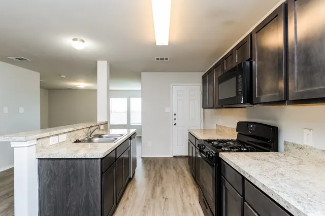 a kitchen with a sink stove top oven and cabinets