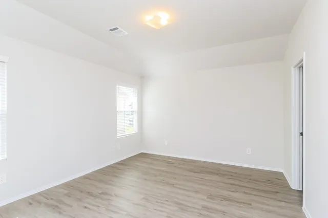 a view of empty room with wooden floor and fan