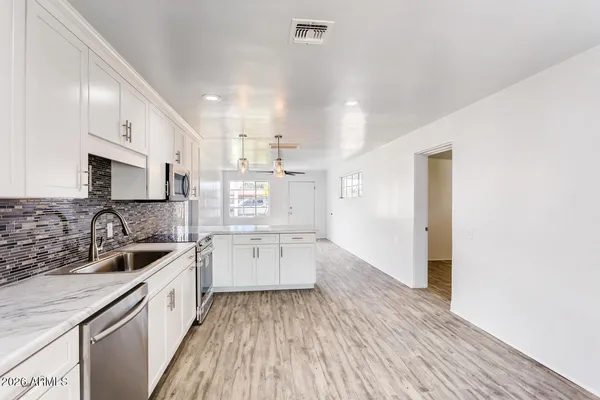 a kitchen that has a lot of cabinets in it and wooden floors