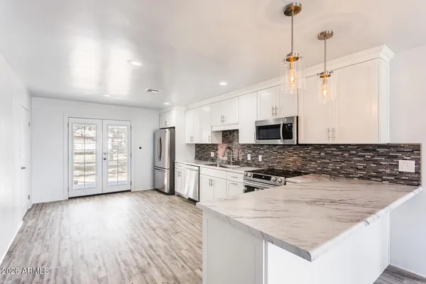a kitchen with stainless steel appliances granite countertop a stove top oven a sink dishwasher and a refrigerator with wooden floor