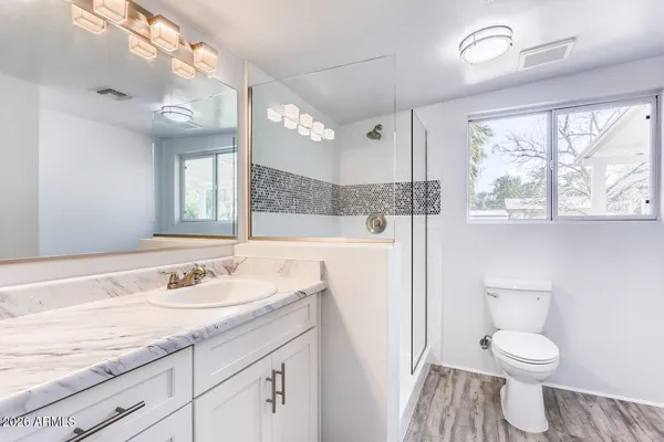 a bathroom with a sink a toilet a mirror and a window