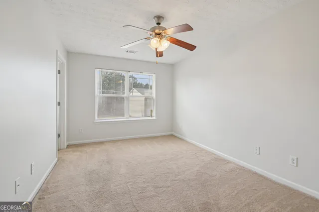 an empty room with chandelier fan and windows
