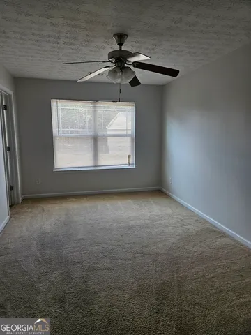 an empty room with a ceiling fan and window