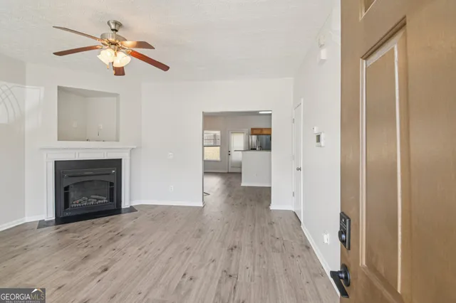 a view of a livingroom with a fireplace a chandelier fan and wooden floor