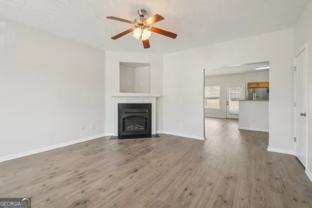 a view of empty room with wooden floor and fan