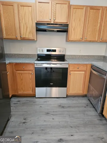 a kitchen with granite countertop wood cabinets stainless steel appliances and a sink