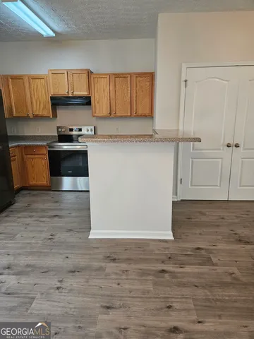 a kitchen with granite countertop a refrigerator and a stove top oven
