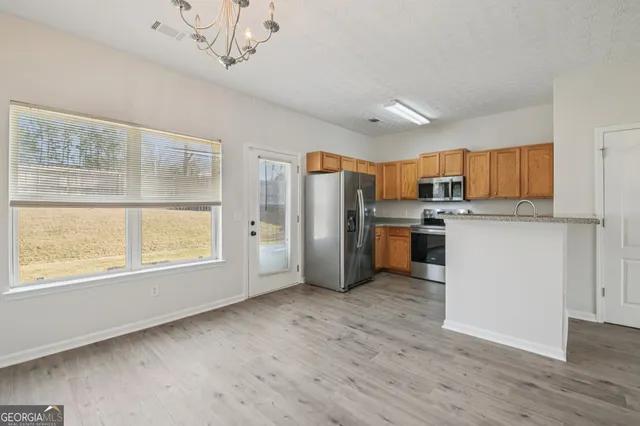 a kitchen with stainless steel appliances a refrigerator a stove a sink dishwasher a oven with white cabinets and wooden floor