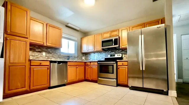 a kitchen with stainless steel appliances granite countertop a refrigerator a stove top oven