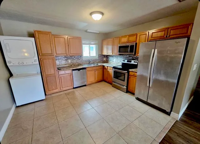 a kitchen with stainless steel appliances granite countertop a refrigerator oven a sink a washer and dryer
