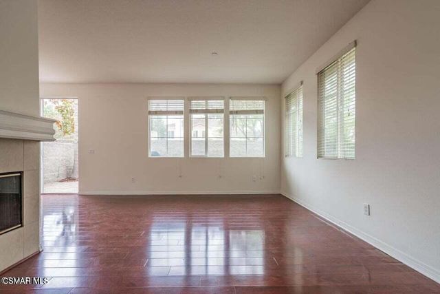 a view of an empty room with wooden floor fireplace and a window