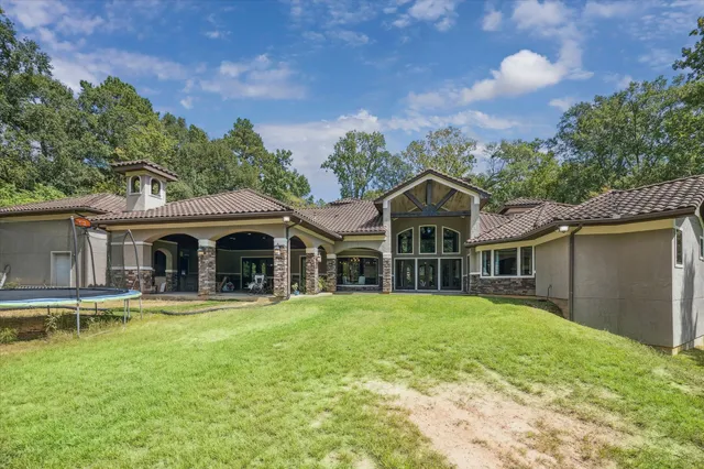 a view of a house with a small yard and a large tree